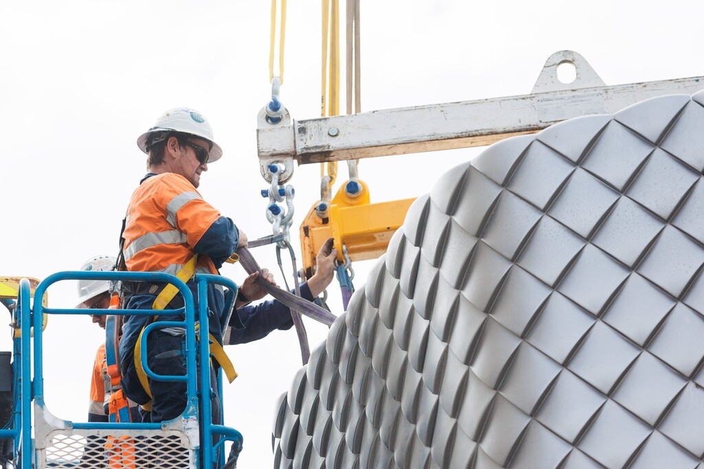 SA Construct crew in a boom lift guiding a craned module of a patterned exhaust stack